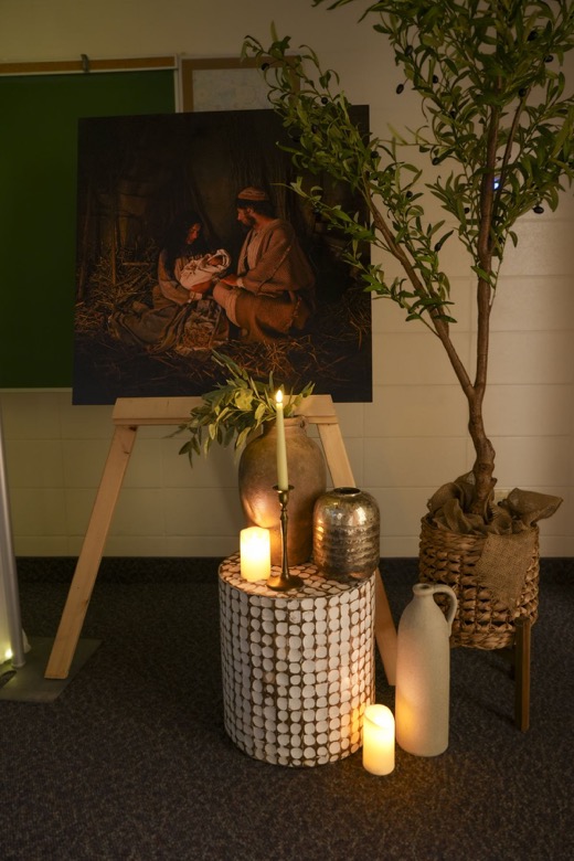 A painting of Mary and Joseph with the newborn Christ, beside candles and clay jars.